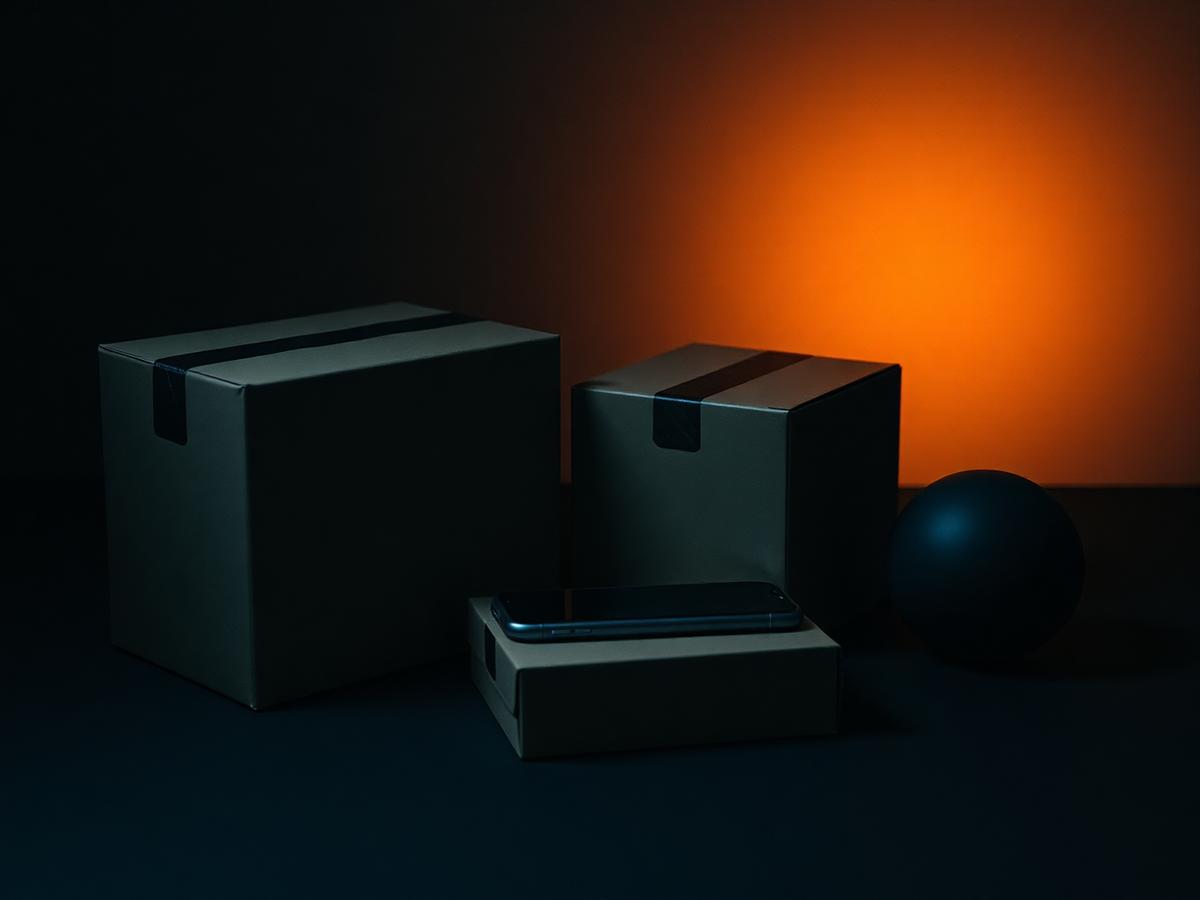Unbranded ecommerce shipping boxes and a phone lit by warm light